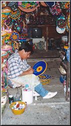 AN ARTISAN PAINTING HIS CERAMICS AT THE MERCADO, ZIHUATANEJO, GUERRERO, MEXICO
